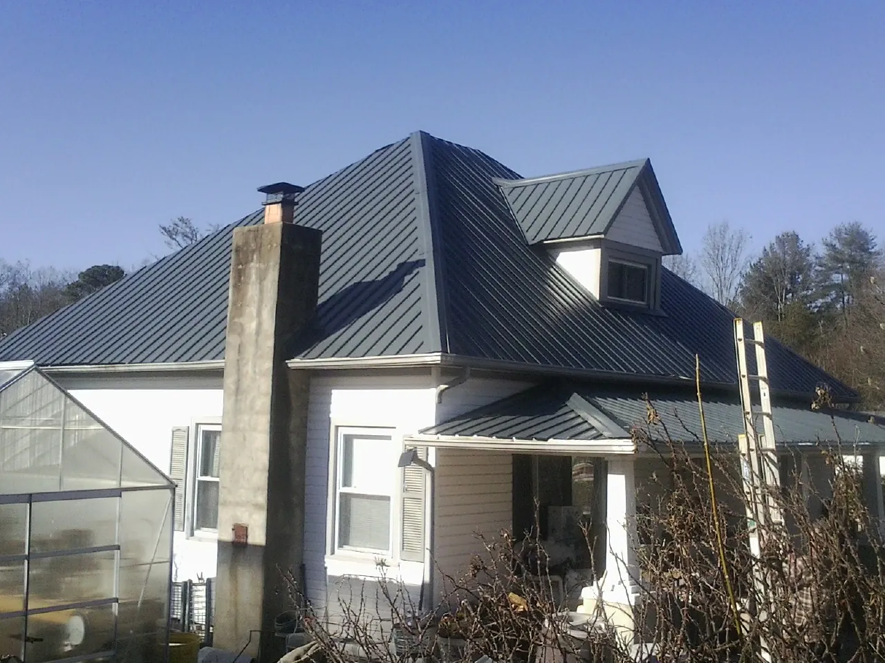 Dark blue standing seam metal roof on a white farmhouse with dormer — Slate & Tile Roof Repair by Roofing Brothers in Moses Lake