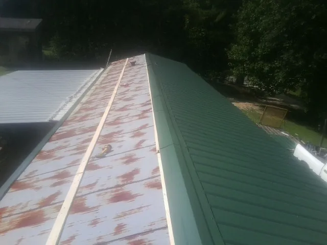 Old rusted panels beside newly installed green metal roofing — Wind Damage Roof Repair by Roofing Brothers in Moses Lake