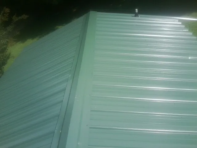 New green metal panels meeting at the ridge of a roof — Flat Roof Repair work by our crew in Moses Lake