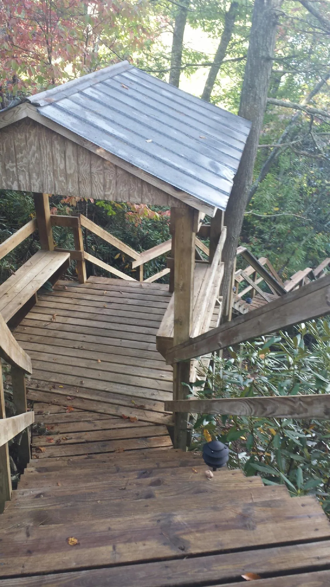 Metal roofed shelter over wooden steps on a wooded walkway — Skylight Repair & Installation work by our crew in Moses Lake