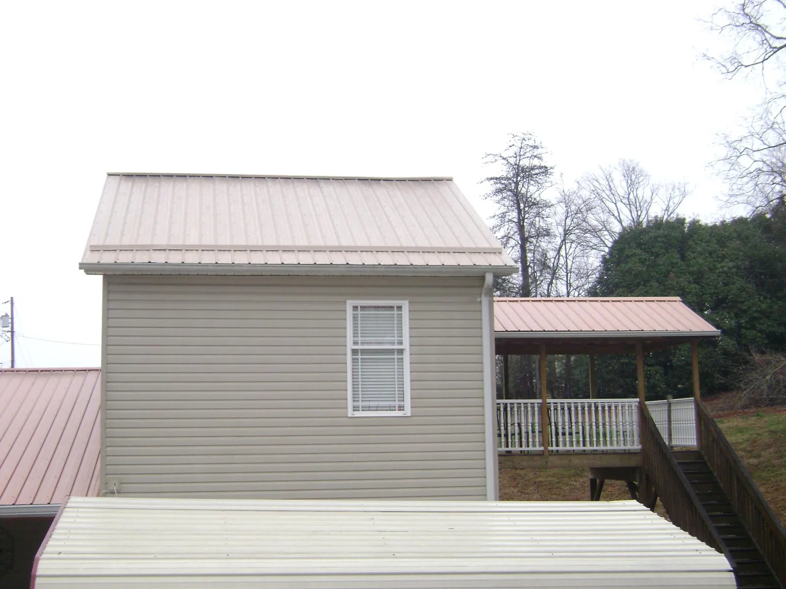 Tan metal roofs on a two story addition and attached porch, from a Roof Replacement job in Moses Lake