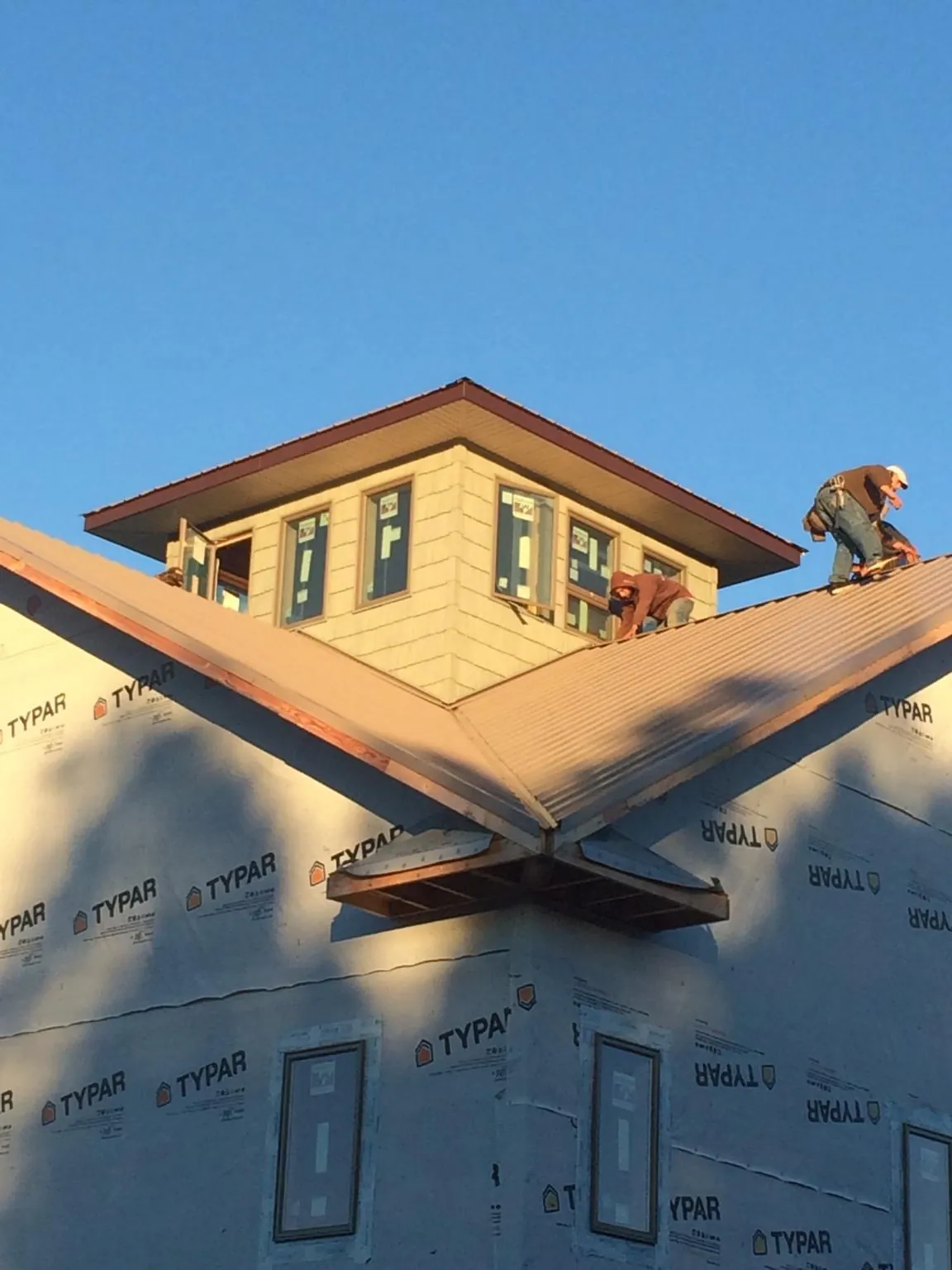 Roofers working around a rooftop cupola on a new metal roof at sunset — Roof Waterproofing in Moses Lake by Roofing Brothers